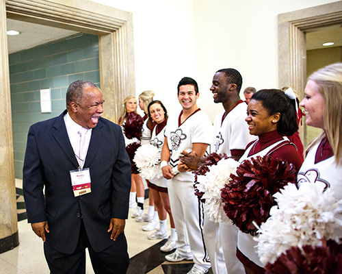 Photo of a man and a group of students smiling